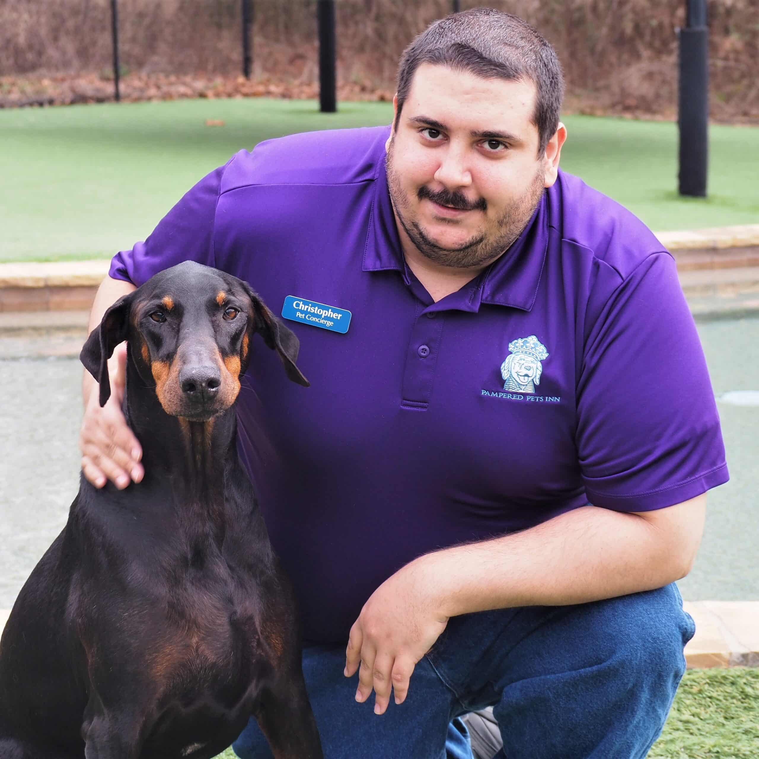 Staff member posing with a dog in front of the pool