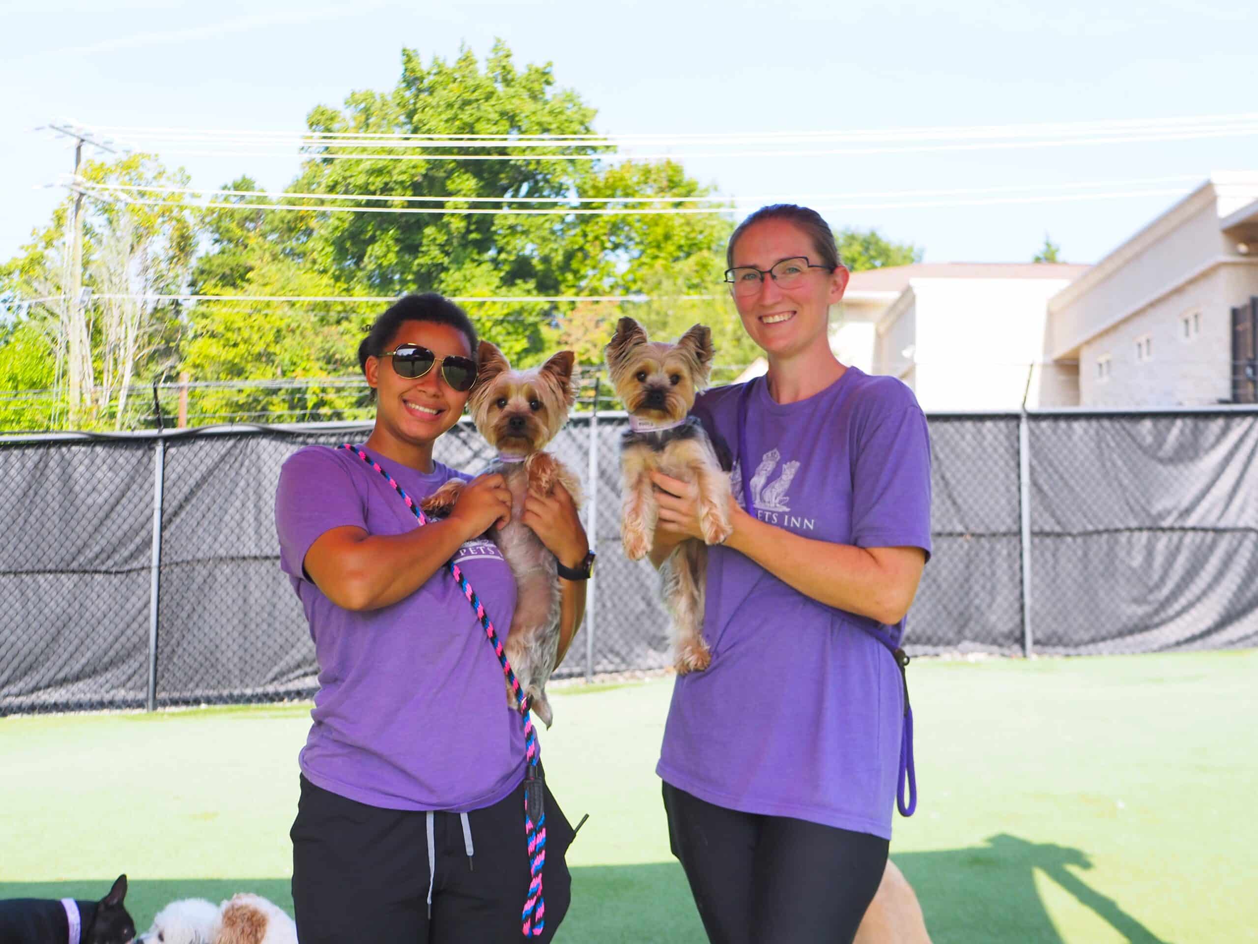 2 staff members holding dogs