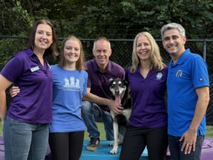 five people posing for a picture with a dog