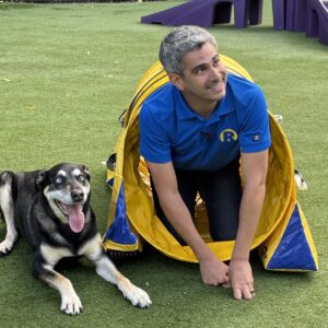 a dog and person posing in front of an agility tube. 
